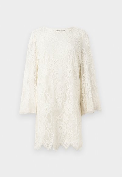 Valkoinen pitsinen pitkähihaista mekkoa, jossa on kukkakuosia, aallotettu helma ja hieman levenevät hihat, taustan yksinkertaisella taustalla.