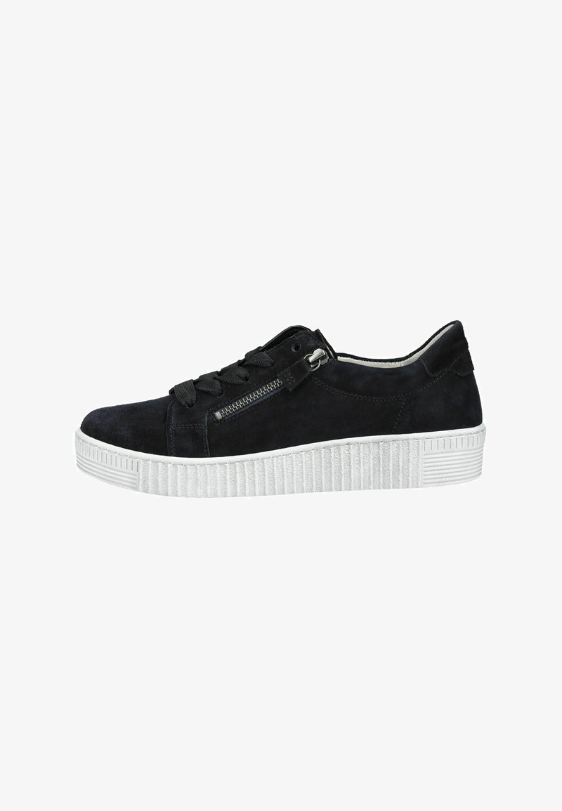 Baskets basses en daim noir avec une semelle blanche épaisse et striée, des lacets noirs, et une fermeture éclair fonctionnelle argentée sur le côté.