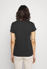 Czarny krótki t-shirt z krótkim rękawem i okrągłym dekoltem, wykonany z miękkiej tkaniny. Posiada prosty design bez widocznych wzorów czy akcentów.