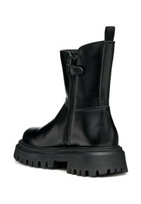 Botín de cuero negro hasta el tobillo con cremallera lateral, suela de goma gruesa y tira en la parte posterior. Acabado liso con detalles de costura visibles.