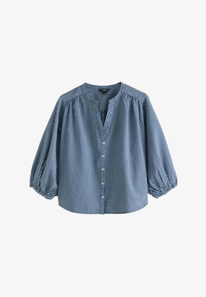 Kék-fehér kockás blúz hosszú, fodros ujjakkal, gombos elülső résszel és kis kerek nyakkivágással.