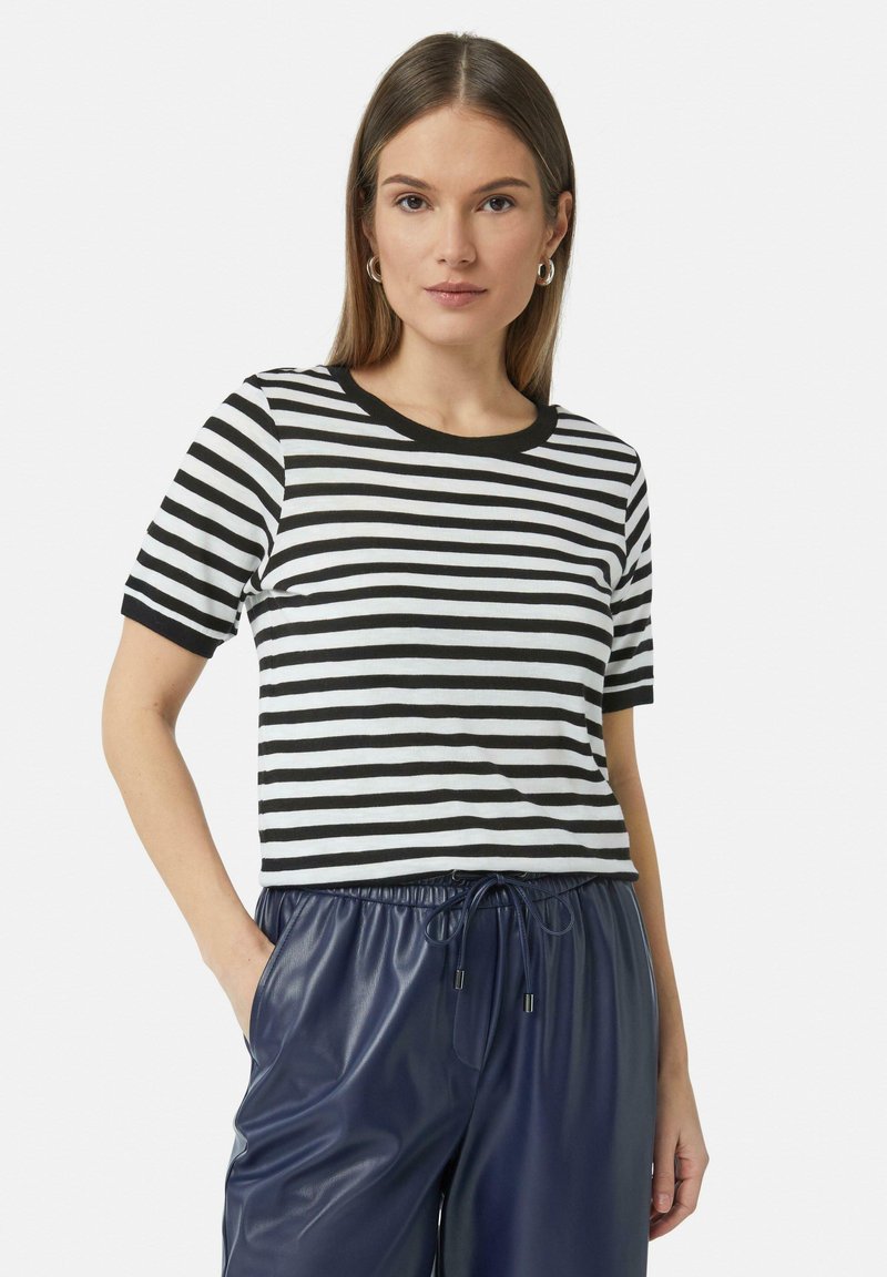 Czarny i biały pasek krótki rękaw t-shirt z okrągłym dekoltem i czarnymi wykończeniami, w zestawie z granatowymi spodniami z materiału imitującego skórę.