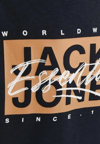 T-shirt en coton bleu marine ornée d'un grand graphique rectangulaire orange avec les mots 'Jack & Jones' en lettres cursives blanches et en lettres majuscules.