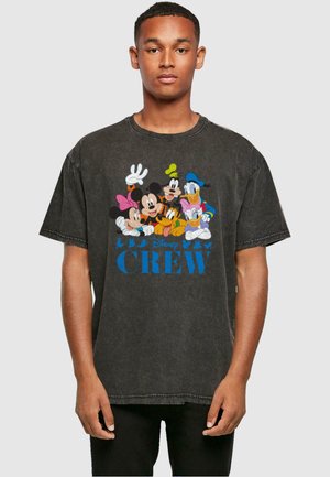 Black oversized T-shirt featuring colorful Disney characters. Design includes "Disney CREW" in bright blue text. Distressed texture, casual style.