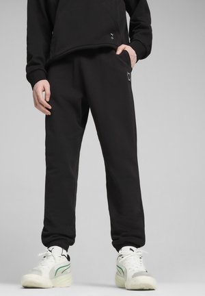 Pantaloni della tuta neri realizzati in morbido materiale, con vita e polsini elastici, e un piccolo dettaglio con logo sulla coscia sinistra.