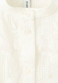 Blusa bianca con un motivo floreale testurizzato, presenta un colletto alla mandarino e tre bottoni sulla parte anteriore, realizzata in tessuto leggero.