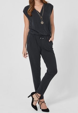 Musta shortseihin leikattu haalari, jossa on lyhyet hihat, v-pääntie, joustava vyötärö ja kiristysnauha. Yhdistetty mustiin remmikkäisiin korkeakorkoisiin kenkiin. Sileä pinta.