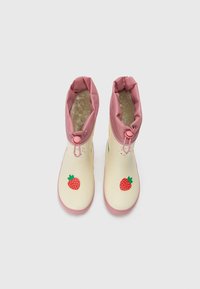 Stivali in gomma con corpo crema e risvolto rosa, decorati con grafica di fragole rosse e un interno in peluche. Chiusura regolabile per adattabilità.