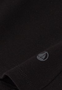 T-shirt en coton noir au toucher lisse, arborant un petit logo gris entouré d'une forme circulaire près de l'ourlet.