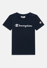 T-shirt en coton bleu marine à manches courtes, avec le logo blanc "Champion" sur le devant et des détails de boutons-pression sur l'épaule.