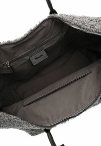 Halli udune kandekott, mille siseküljel on mustast kangast vooder, lukuga tasku ja organisatsiooni jaoks libistatav tasku.