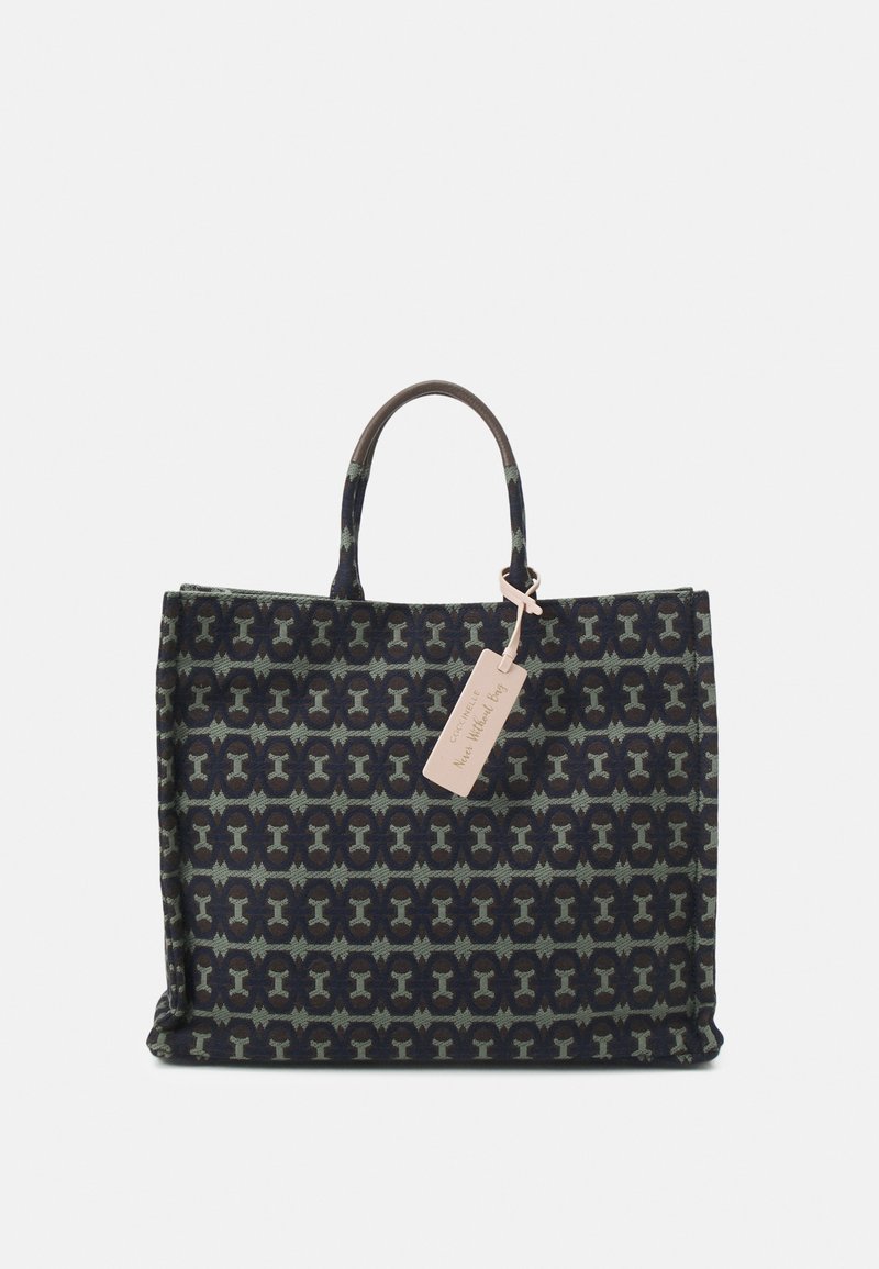 Sac fourre-tout en tissu foncé à motifs, avec deux anses et une étiquette claire attachée près de la poignée supérieure.