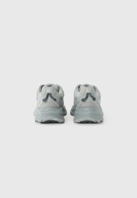 Pantofi sport gri deschis cu un upper din plasă, călcâi întărit, talpă texturată și accente în gri mai închis. Prezintă un design aerodinamic.