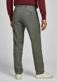 Grijze, gestructureerde broek met een rechte snit, voorzien van twee achterzakken en gedragen met witte sneakers. Subtiel patroon en op maat gemaakt ontwerp.