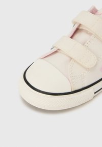 Κοντινή λήψη μπεζ πάνινης αθλητικής κάλτσας με δύο λουριά βέλκρο και λαστιχένιο κάλυμμα στα δάχτυλα, πάνω σε λευκό φόντο.