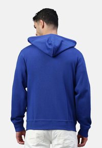 Felpa con cappuccio blu royal in misto cotone, con cappuccio ampio, polsini e orlo a costine. Tessuto morbido con colore uniforme.