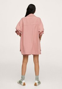 Zbyt duża różowa kurtka z kołnierzem, podwiniętymi rękawami i bocznymi kieszeniami. Nosi się ją na krótkim ubraniu, w połączeniu ze skarpetkami i trampkami.