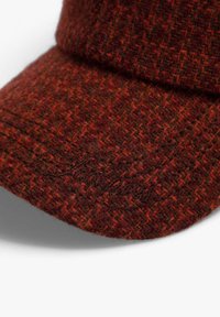 Gorra de lana con un patrón de espiga en tonos de rojo y marrón, con una visera estructurada y una tela texturizada.