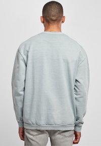 Světle modrá mikina s kulatým výstřihem, žebrovanými manžetami a spodním lemem. Měkká textura s volným střihem a minimem švů.