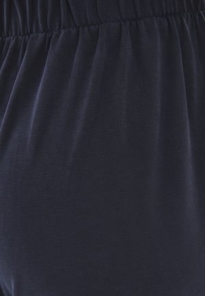 Gros plan sur une ceinture noire élastique sur un tissu doux froncé, montrant la texture et le détail de l'élasticité.