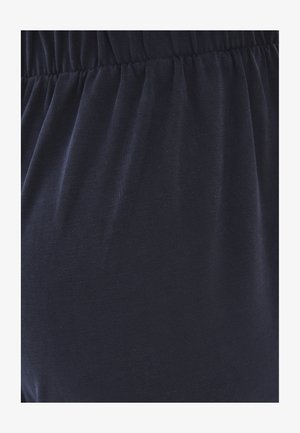 Gros plan sur une ceinture noire élastique sur un tissu doux froncé, montrant la texture et le détail de l'élasticité.