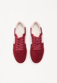 Baskets en daim rouge profond avec des accents en cuir rose. Dotées d'un dessus texturé, d'un bout rond et de lacets plats. Design simple et sportif.