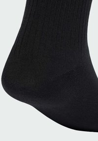 Čierna rebrovaná členková ponožka vyrobená z jemného materiálu, s hladkým švom na prstoch a strednou hrúbkou so semi-matnou textúrou.