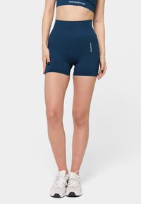 Navy korkeavyötäröiset urheilushortsit, jotka on valmistettu joustavasta kankaasta. Ominaisuuksiin kuuluu kiinteä muotoilu ja pieni valkoinen logo vasemmalla puolella.