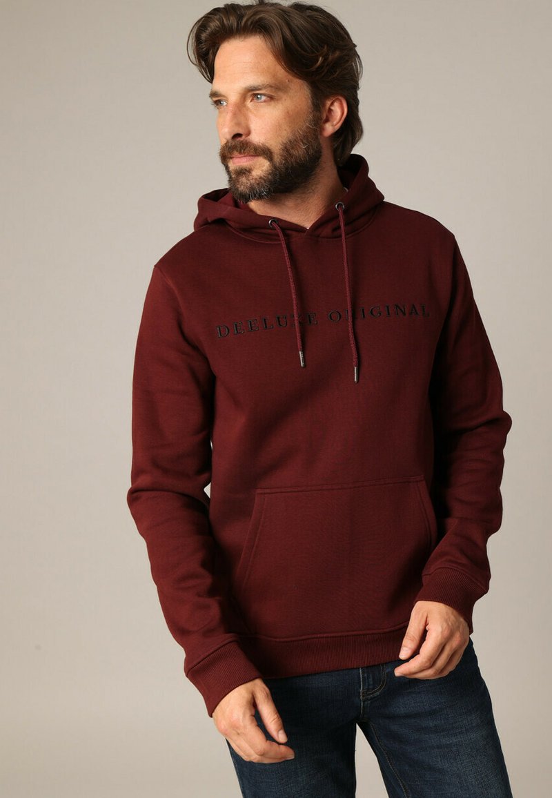 Bordeaux hoodie met een kangoeroe-pocket, een capuchon met trekkoord en zwarte "DEE LUXE ORIGINAL" tekst op de voorkant. Gladde katoenmix stof.