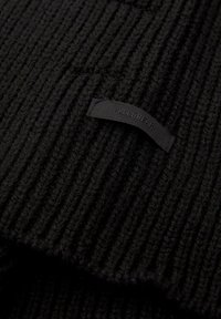 Tessuto a maglia nera a coste con un design testurizzato, con un'etichetta a pull tab nera che recita "PULL&BEAR", visibile vicino al bordo.