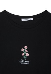 T-shirt di cotone nero con ricamo floreale in rosa e verde, con il testo "Fiorisci CON GRAZIA" sotto il design.