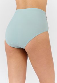 Lichtblauwe naadloze hoogwaist onderbroek gedragen door een persoon, die de achterkant en bovenbenen toont tegen een effen witte achtergrond.