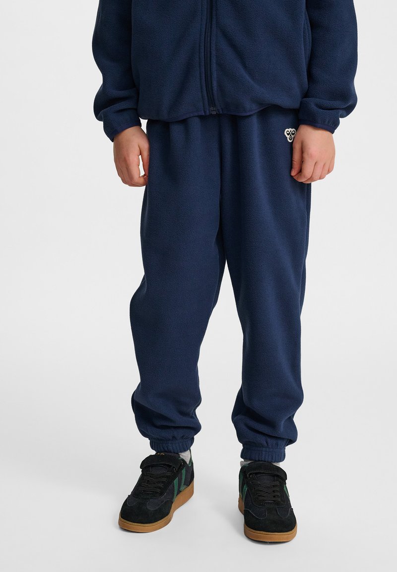 Mörkblå fleece-träningsdräkt med en zip-jacka och byxor med elastisk midja; har en liten logotyp på byxorna och ribbade muddar vid anklarna.