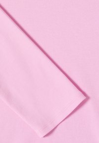 Tissu en coton rose clair, texture lisse, avec une manche pliée et un ourlet cousu proprement, mettant en avant un design simple sans texture.