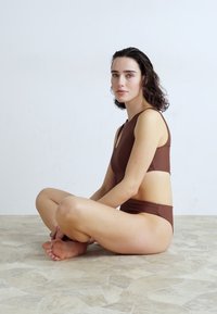 Brun to-delt badetøy med cropped topp og høyt liv, laget av glatt stoff, med minimalistisk design og utskjæringer.