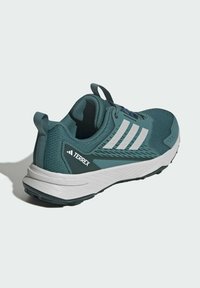 Teal løbesko med hvide accenter, tekstiloverdel, polstret sål og forstærket hæl. Har Adidas-logo og Terrex-branding.