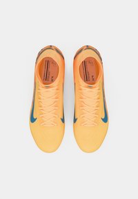 Scarpe da calcio arancioni con dettagli blu, dotate di una parte superiore testurizzata, lacci piatti e un design a taglio basso per agilità e supporto.