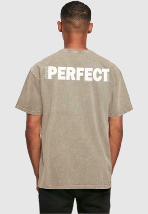Khaki bomulds-t-shirt med en afslappet pasform. Har stort hvidt tekst på ryggen, der står "BELIEVE PERFECT YOU ARE." Korte ærmer.