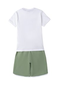 Kurzes weißes T-Shirt mit Rundhalsausschnitt und grünen Shorts. Glattes Material, lockere Passform und elastischer Bund mit weißem Rand.