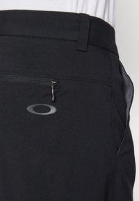 Zwarte shorts met een ritszak aan de zijkant en een reflecterend logo. Gemaakt van een soepele stof met een casual ontwerp en een gestructureerde tailleband.