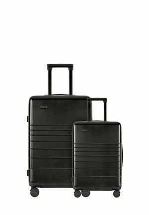 Black hardshell luggage set, featuring a larger and smaller case, with vertical ridges, retractable handles, and four smooth-rolling wheels.