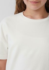 Witte katoenen t-shirt met een ronde hals. Gladde textuur, korte mouwen en een minimaal ontwerp.