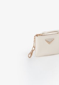 Piccola pochette in pelle crema con catena dorata e chiusura, tracolla e targhetta triangolare dorata con la scritta "MIRIADE."