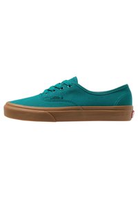 Baskets en toile turquoise à profil bas, avec un design à lacets et une semelle extérieure en caoutchouc marron ; comportent des coutures discrètes et un détail de logo.