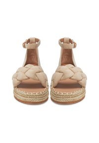 Smėlio spalvos zomšiniai espadrilų sandalai su pintomis dirželiais, čiurnos sagtimi ir platformos padu, apvyniotą jūžute. Lygi ruda pėdos dalis.