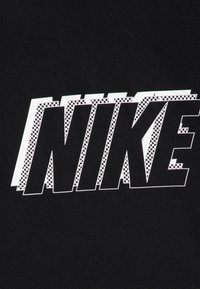 Tejido negro con la palabra "NIKE" en blanco audaz y un patrón de tablero de ajedrez en los bordes, enfatizando un diseño dinámico.