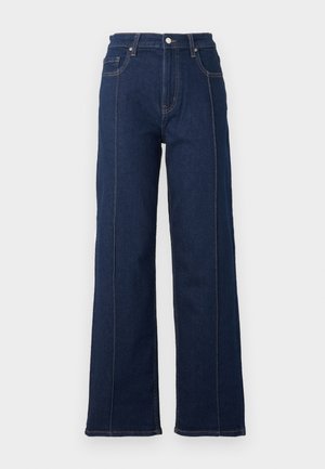 Mørkeblå denim vid ben-jeans med fremtrædende syninger, høj talje og fem lommer. Har lukning med knap og lynlås foran.