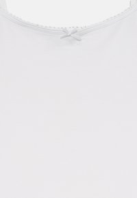 White cotton tank top with a round neckline, scalloped trim, and a small decorative bow at the back. Smooth texture and regular fit.