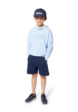 Sweat à capuche bleu clair avec le logo "BOSS", shorts navy avec un motif subtil, casquette navy, et chaussures de sport foncées avec des accents blancs.