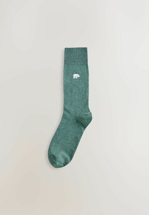 Grønne bomuldsokker med ribbet kant og en broderet detalje af en isbjørn. Blød struktur og standard sokform med afrundet tå.